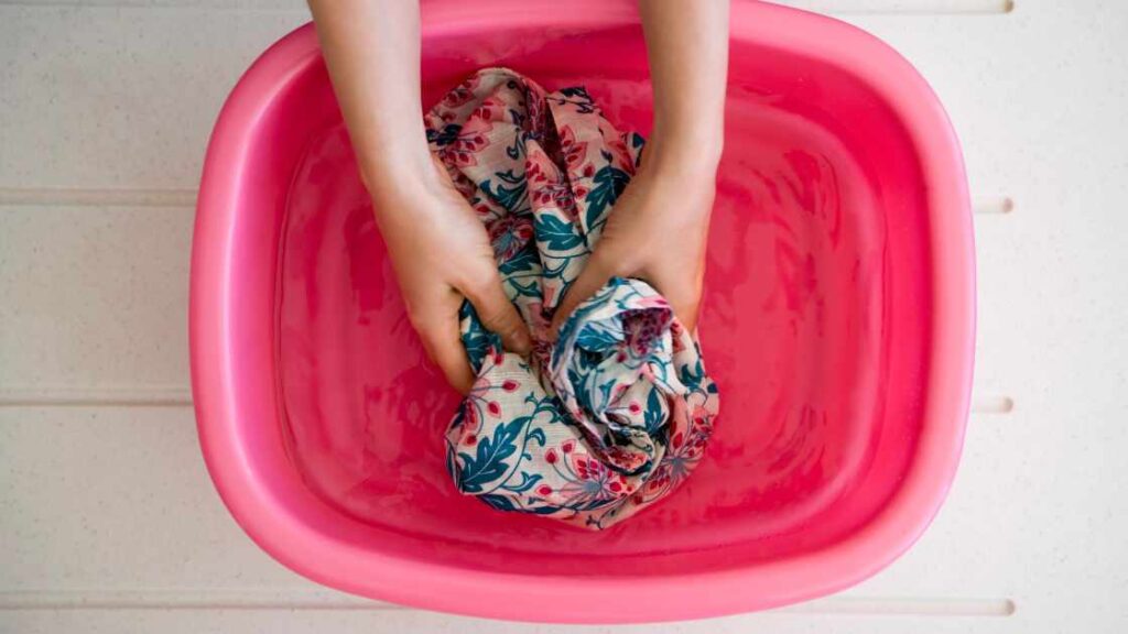 A person washing a shirt in tub representing the query: How to wash sublimation shirts?