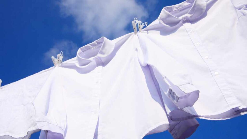 Two white shirts hanging in open air represnting the query: How to wash sublimation shirts?