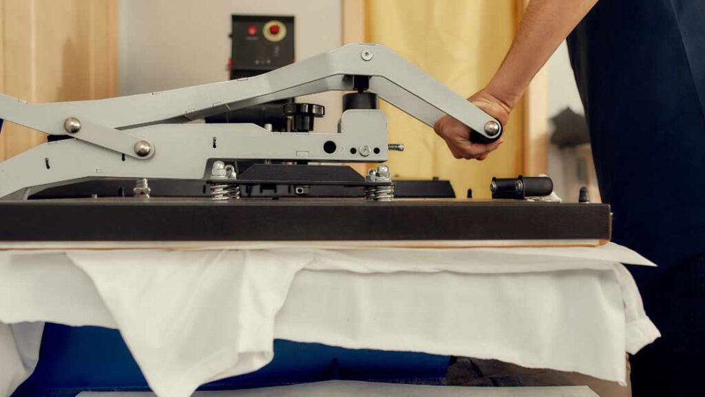 A persong pressing heat press on a shirt representing the query: Why is my sublimation faded ?