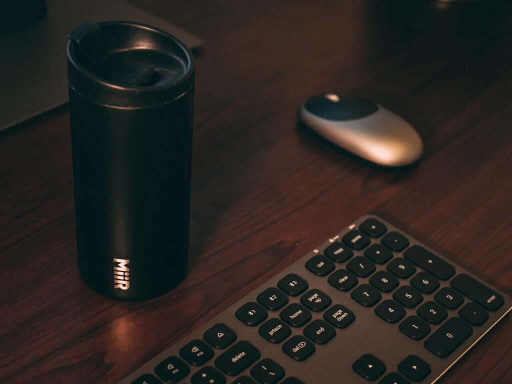 A Steel tumbler mouse and keyboard lying on the table representing the query : Sublimation on stainless Steel . Can you sublimate on stainless steel or sublimating on stainless steel.