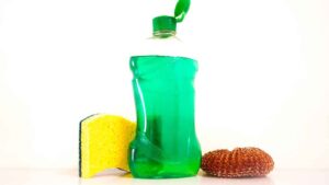 A dish soap bittle with sponge representing the query: How to get transmission fluid out of clothes with dish soap?