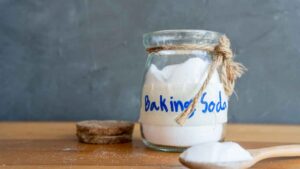 A jar full of baking soda with a spoonful of baking soda representing the query: How to get transmission fluid out of clothes with baking soda?