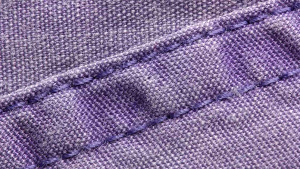 A close up image of seams and hems of a fabric after finishing representing the query: How long does it take to make a dress?