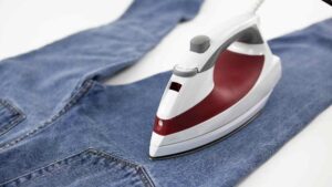 An iron on a jeans representing the query: How to soften stiff thick jeans with iron?