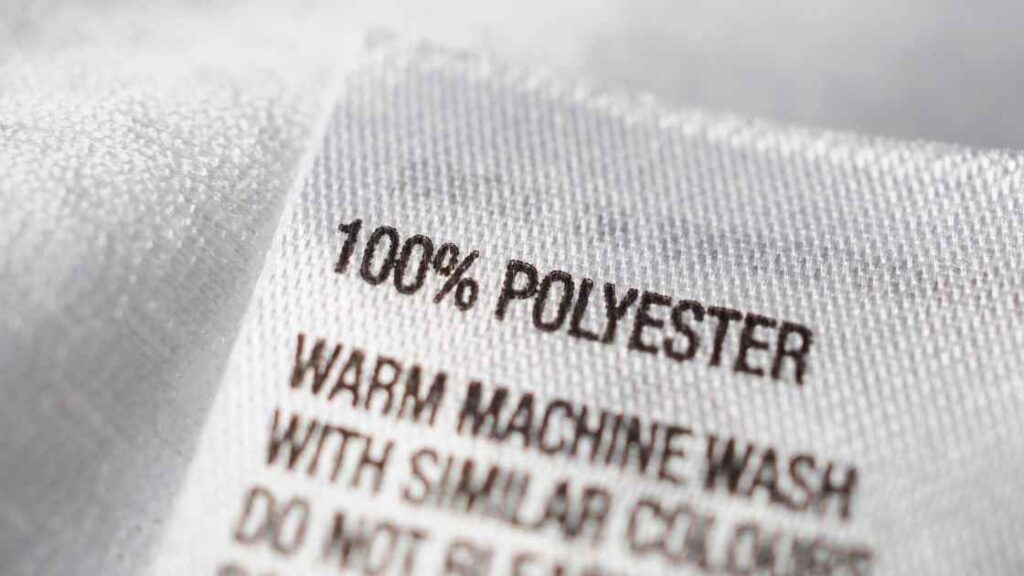 A fabric tag with fabric properties written on it like 100 percent polyester and warm machine and similar colors wash etc. representing the query: Can you tie dye polyester? Or Can you tye dye polyester? Or Can polyester be tie dyed? Or Can i tie dye polyester? Or Does polyester tie dye? Or How to tie dye polyester?