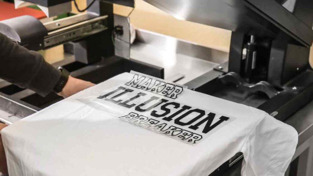 A black colored wording design printed from a sublimation printer lying on a white t shirt in heat press representing the queries: What is Sublimation Printing ?