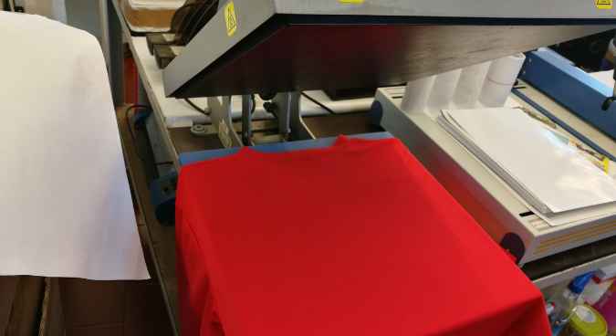 A red colored Shirt ready to be sublimated lying into the heat press representing the queries: What is Sublimation Printing ?