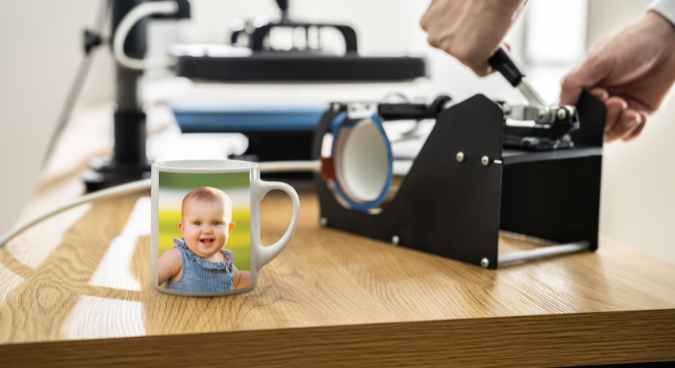 A person Printing a baby face on mugs with mug press representing the queries: What is Sublimation Printing ?