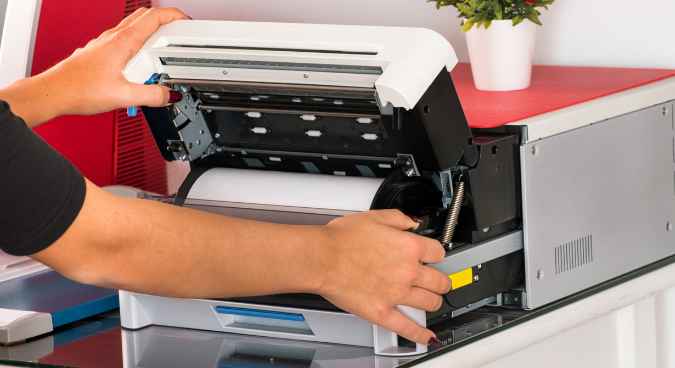 A person operating a Sublimation printer representing the queries: What is Sublimation Printing ?