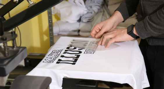 A person removing film from the print from the white shirt representing the queries : Types of shirt printing Or Types of t shirt printing Or Different Types of Shirt printing Or Types of printing on shirt Or Different Types of t shirt printing Or Different types of tshirt printing.