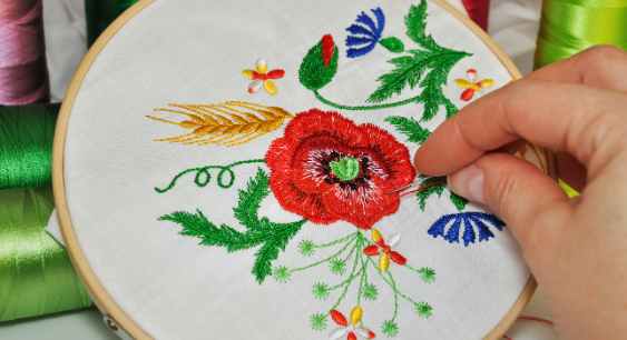 A person sweing a flower design to the cloth through embroidery represneting the queries: Types of shirt printing Or Types of t shirt printing Or Different Types of Shirt printing Or Types of printing on shirt Or Different Types of t shirt printing Or Different types of tshirt printing.